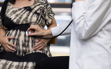 Doctor using stethoscope listening to baby heartbeat of pregnant woman. Doctor listens to a pregnant woman's heartbeat with a stethoscope, creating a moment of trust and connection.