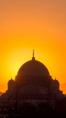 Fototapeta premium Silhouette of a magnificent mosque at sunrise, bathed in warm golden hues.