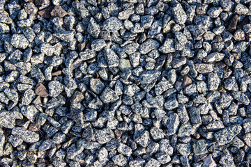 Textured gravel surface composed of small, irregular stones in various shades of gray, creating a natural and rugged appearance suitable for landscaping and construction projects