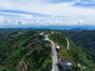 Breathtaking high-angle shot of a winding, asphalt road as it curves through a lush, verdant mountain range and valley.