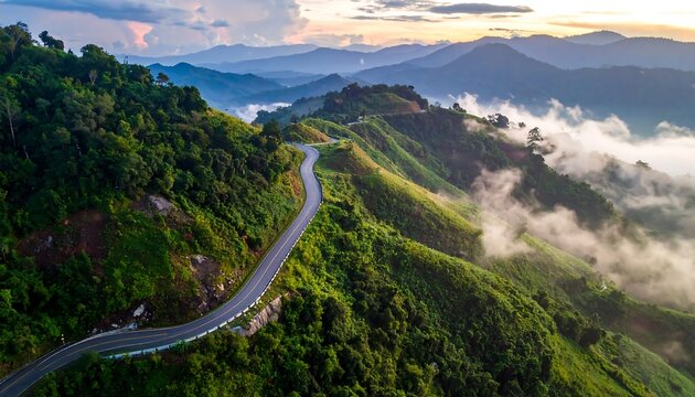 Winding road through lush mountain range at sunrise