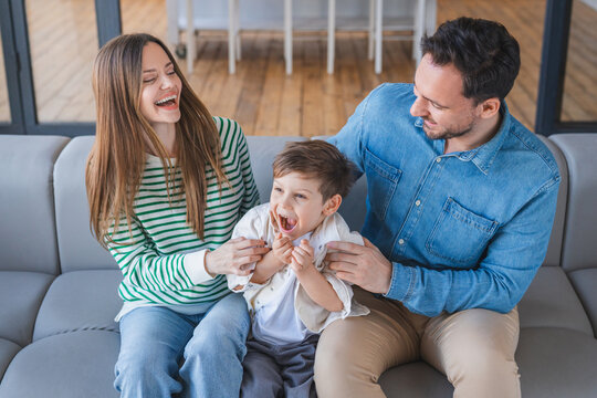 Family, laughing and tickle in home portrait, funny games and goofy bonding for love connection. Parents, son and kid for happiness in living room on weekend, mother and father for fun at home - Powered by Adobe