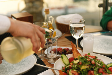 Closeup of Waiter Pouring Raki at Sunset