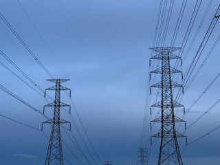 High-voltage electric poles and power lines against a blue sky. High-voltage electric poles with cables. Electric transmission lines on high-voltage electric poles.