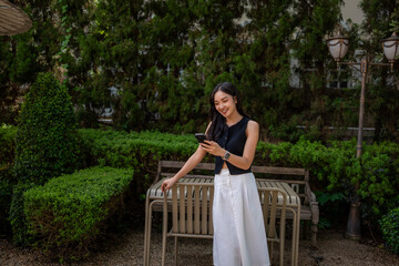 Naklejka premium Young woman enjoying connection with smartphone in garden