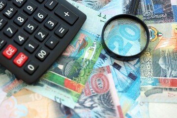 Kuwaiti dinar currency money bills and calculator with magnifying glass. The concept of taxation and money count