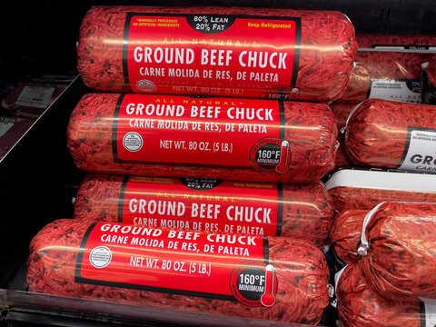 Fresh ground beef chuck hamburger meat tubes on display in an American grocery store butcher shop.