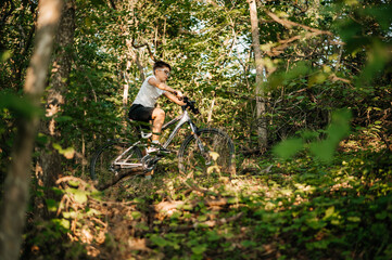 A young boy joyfully riding his mountain bike along a scenic lush forest trail surrounded by nature