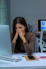 Asian woman suffering from headache and eye strain at office