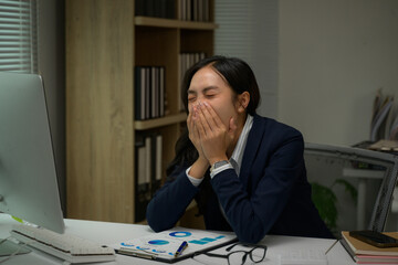 Naklejka premium Businesswoman yawning covering mouth feeling tired working late