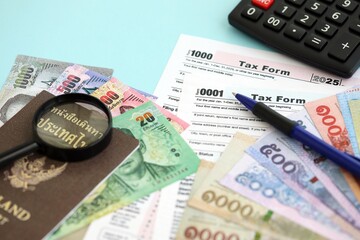 Thai baht money bills and calculator with tax form on blue. Taxation and accounting concept