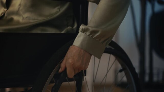 Senior woman in wheelchair moving to desk, opening laptop for remote home work