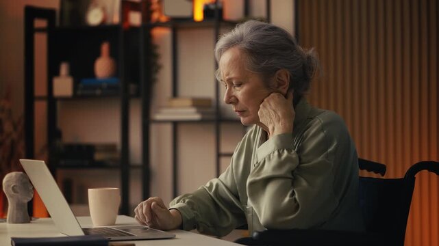 Sad elderly lady in wheelchair reading bad news on laptop, hospital bill problem