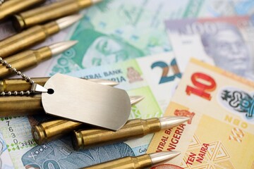 Nigerian naira currency money bills and rifle bullets with dogtag. The concept of warfare and army...