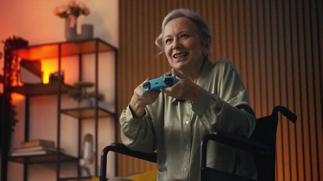 Excited senior female in wheelchair playing video game with joystick, pastime
