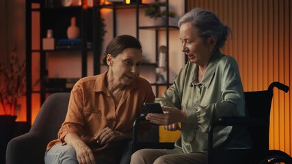 Woman and her friend in wheelchair looking at photos in social network app