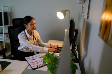 Female Asian doctor working on computer at night in office