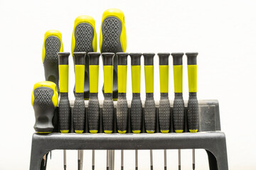 Set of yellow and black screwdrivers arranged in a holder on a white background
