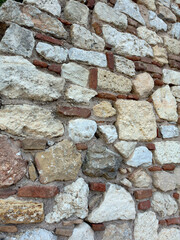 Rustic stone wall with cream blocks and a single red brick detail, ideal textured background for design projects.