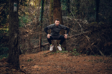 Determined male athlete jumping during intense forest workout