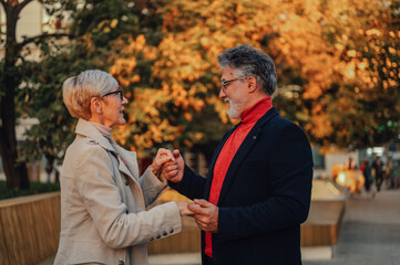 Senior couple holding hands in autumn park, expressing love and togetherness