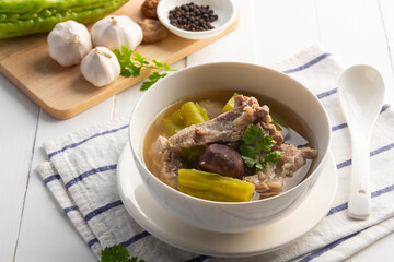 Bitter gourd soup with pork baby back spare rib or pork cartilage in white bowl.