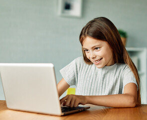 Fototapeta premium Portrait of a teenage girl having fun using laptop or doing homework with laptop at home