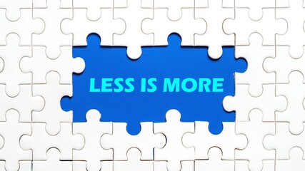 Fototapeta premium The concept of writing LESS IS MORE in the middle of the puzzle with a blue background.