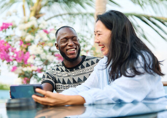 Portrait of a couple young people hangout in the city , sitting in a cpffee shop or bar table taking a selfie photo with a smartphone together and having fun.