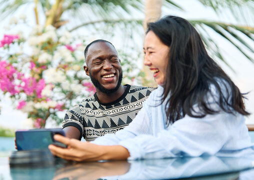 Portrait of a couple young people hangout in the city , sitting in a cpffee shop or bar table taking a selfie photo with a smartphone together and having fun.