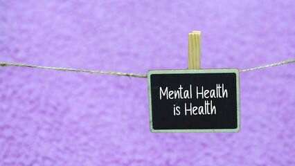 concept of writing Mental Health Is Health on a mini blackboard. purple background.