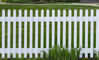 White wooden picket fence with green lawn