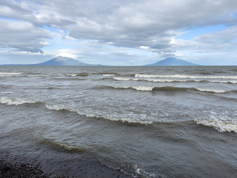 Majestic twin volcanoes rise above choppy waters under cloudy sky in Nicaragua