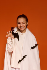 Cute girl dressed for Halloween fun on a vibrant orange background