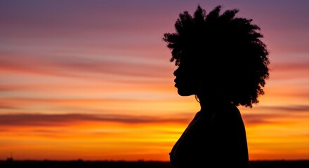 Silhouette of a woman with afro hair against a colorful sky at sunset time full of beauty