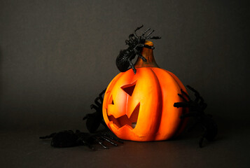 Halloween pumpkin jack-o-lantern decorated with black spiders on dark background, spooky still life symbolizing horror, fear, and festive creepy atmosphere.