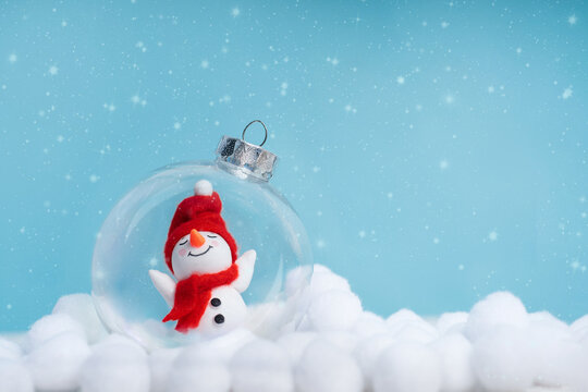 Snowman in glass globe on blue winter background