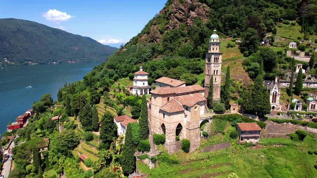Morcote Santa Maria del Sasso church aerial orbit. Cinematic drone flight over Lake Lugano Ticino Switzerland. High resolution 4K travel video. Scenic village panorama.