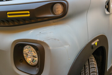 Fototapeta premium A close-up of the car's front bumper with scratches and a fog light. The car has a modern design and an elegant appearance. Driving style in Italy