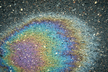 Fototapeta premium Oil slick creating iridescent rainbow colors on asphalt pavement.