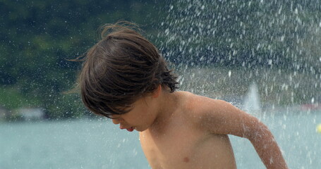 A child with wet hair under a splash of water, highlighting the refreshing and playful moment