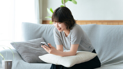 ソファに座ってスマートフォンを使う女性