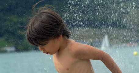 A child with wet hair under a splash of water, highlighting the refreshing and playful moment