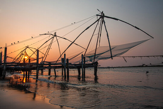 March 25, 2016, in Kochi, India, the iconic Chinese fishing nets rise against a golden sunset, their reflections on the water echoing Kerala&rsquo;s timeless tradition, culture, and coastal heritage.