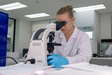 Scientist examining samples under a microscope in a modern laboratory setting during the daytime