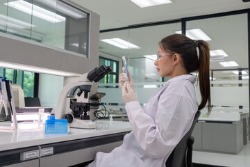 Scientist working with a microscope and samples in a modern laboratory environment during daytime