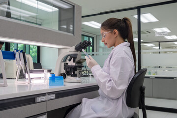 Scientist examining samples under a microscope in a modern laboratory during daytime
