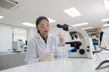 Scientist conducts research in laboratory with microscope and test tubes during daylight hours