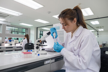 Scientist conducting research in a laboratory with a microscope during daylight hours