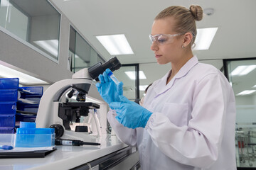 Scientist examines sample with microscope in modern laboratory setting during daylight hours